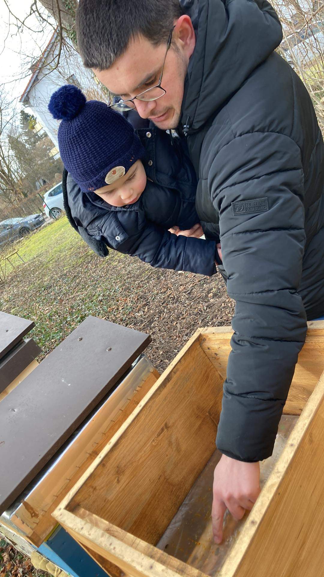 Father and toddler at the hives in a family beekeeping moment