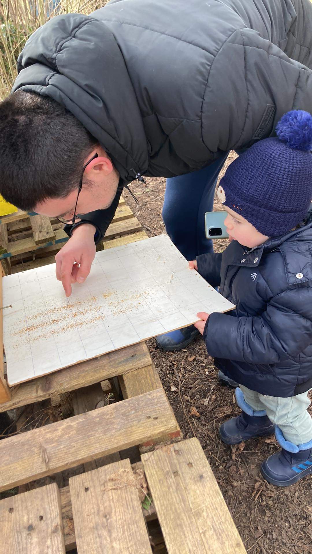 Father and toddler exploring honeycomb frame together at the hives